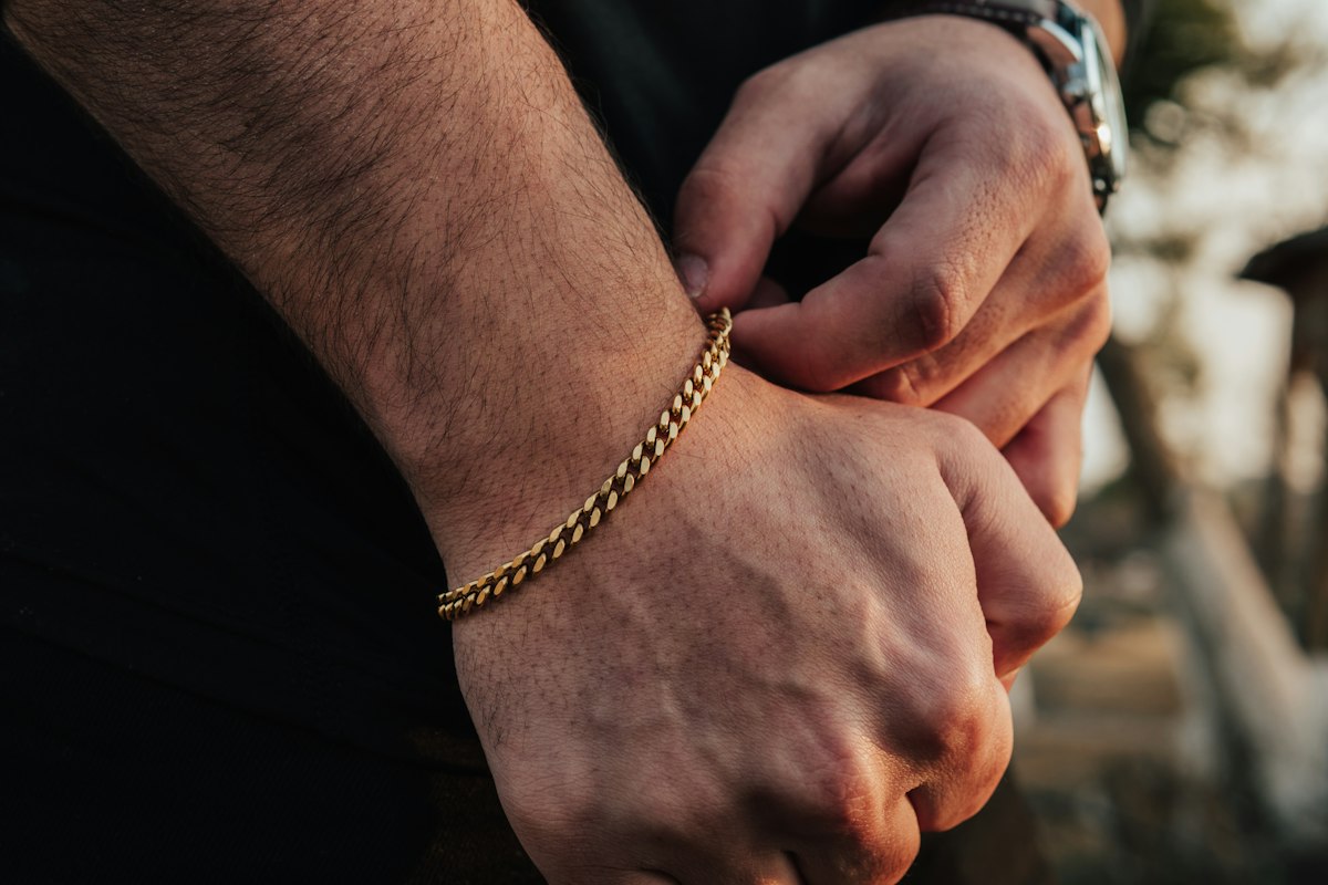 A wrist wearing warm gold bead bracelets in soft natural light