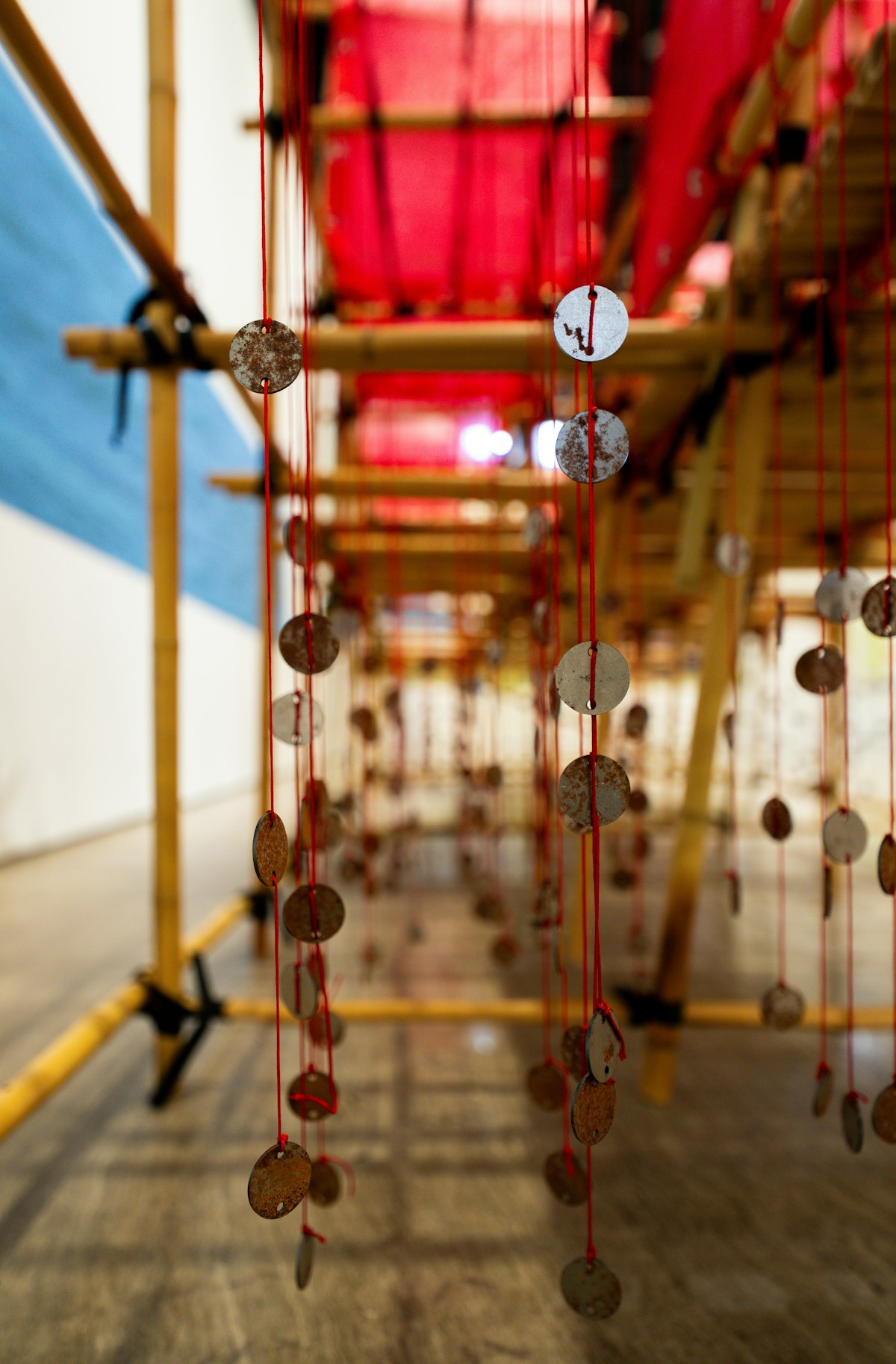 Small coin charms hanging from red strings beneath bamboo