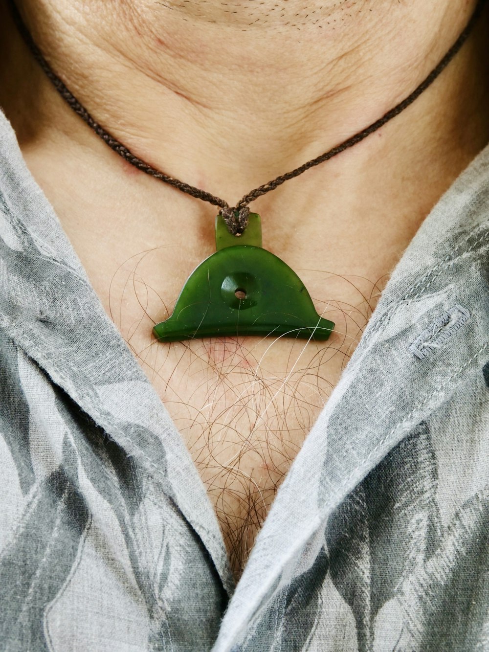 A green jade pendant on a brown cord necklace
